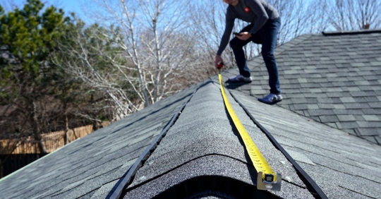 man measuring on top of roof